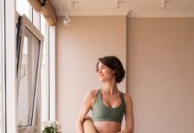 “필라테스, 바쁜 현대인의 새로운 일상 루틴으로 자리잡다” a woman in a green sports bra top and leggings holding a yoga mat